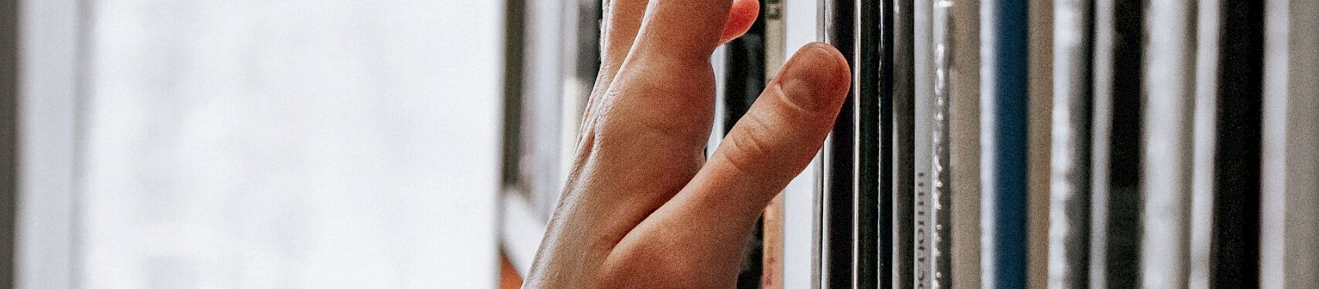 A hand selects a book from a library shelf.