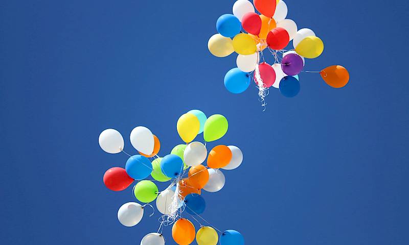 Multicoloured balloons against a blue sky, seen from below