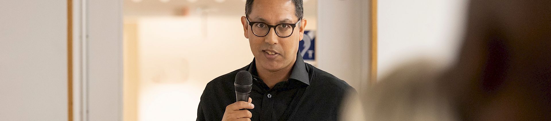 Rishi Dastidar stands up with a microphone in hand.