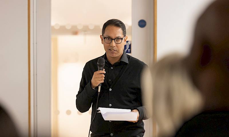 Rishi Dastidar stands up with a microphone in hand.