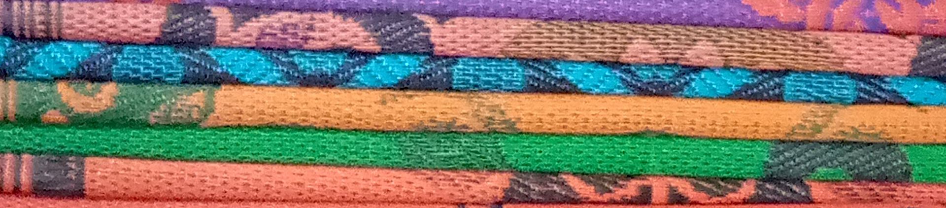Zoomed in photograph of colourful, patterned mats, stacked on top of each other