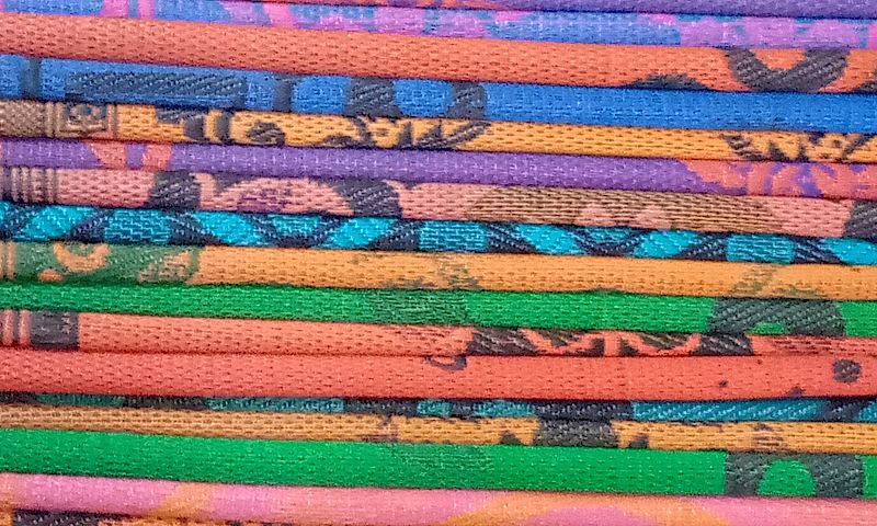 Zoomed in photograph of colourful, patterned mats, stacked on top of each other